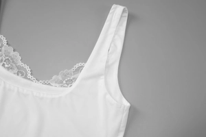 Gros plan sur la bordure en dentelle blanche et le tissu lisse du caraco à col en V