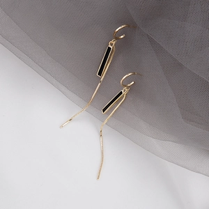 Close-up of elegant gold and black drop earrings with long hanging fringe chains