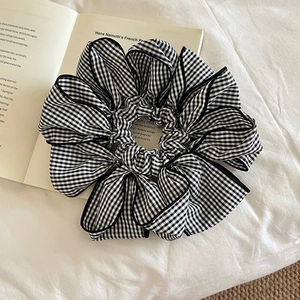 Oversized black and white gingham scrunchie with lace trim on a white fabric background