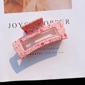 Detail of pink matte acrylic hair claw with red ink splatter and hollow square design
