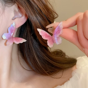 Gros plan de boucles d'oreilles papillon en dégradé rose et violet avec paillettes