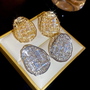 Détail de boucles d'oreilles ovales évidées en or et argent avec zircons étincelants