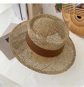 Detail of natural seagrass boater hat with dark brown wide ribbon on top view
