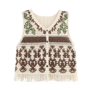 Detail of bohemian crochet vest featuring floral embroidery and knotted fringe hemline