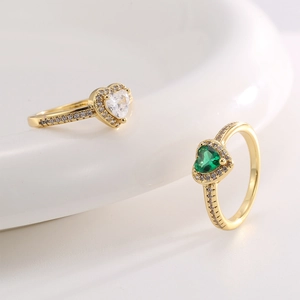 Elegant gold heart rings with pink and green zircon stones on white ceramic base