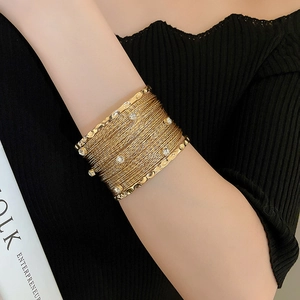 Detailed close-up of a wide multi-layer gold cuff bracelet with sparkling zircon stones