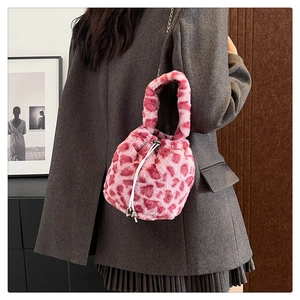 Pink leopard faux fur bucket bag with chain strap shown on model's shoulder in style