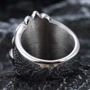 Vintage stainless steel skull ring for men with industrial texture on grey rock background