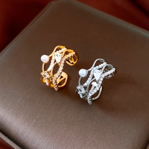 Détail de bagues multicouches en or et argent avec perles et pierres de zircone cubique
