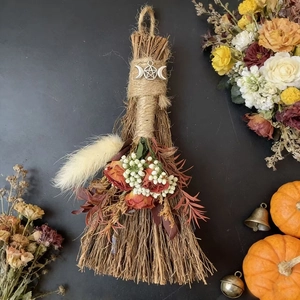 Macro detail of witch broom with silver moon charm and dried flowers on dark background