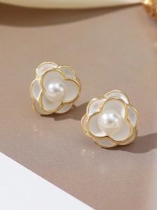 Detailed close-up of white enamel camellia flower stud earring with pearl and gold plating