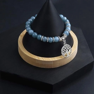 Close-up of tree of life charm and blue stone beads on a black jewelry stand