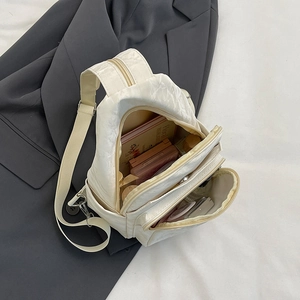Borsa a tracolla in pelle PU plissettata bianco crema su sfondo di giacca grigia