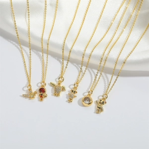 Detail view of gold necklaces with teddy bear, turtle, and astronaut pendants on silk