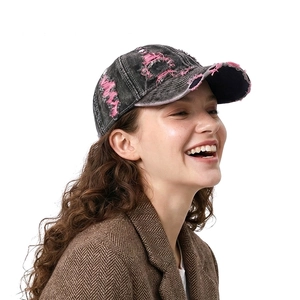 Distressed denim baseball cap with pink frayed holes and curved brim on a side-view model
