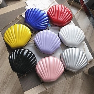 Glossy shell-shaped chain cross-body bags in eight vibrant colors with gold straps