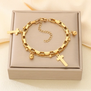 Macro shot of 18K gold plated double layer bracelet with cross and bead charms