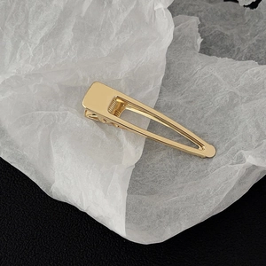 Close-up of golden minimalist metal duckbill hair clip with polished mirror finish