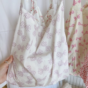 Détail de sacs en coton doux avec nœuds et motifs floraux en rose et violet
