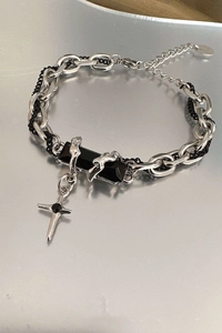 Detail of silver chain bracelet with black stone and cross pendant in punk style