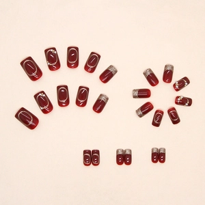 Sparkling burgundy red press-on nails with gold foil, pearls, and glitter decorations