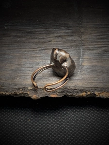 Detailed close-up of a bronze adjustable ring with a dark irregular natural stone gem