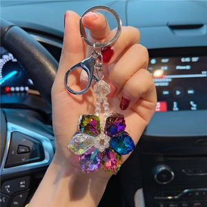 Close-up of a crystal snowflake keychain held against a car steering wheel background
