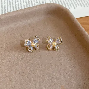 Detailed macro view of gold-plated butterfly earrings with zircon and pearls on a tray