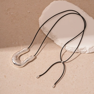 Macro view of fluid silver U-shaped pendant on black rope for minimalist sweater chain