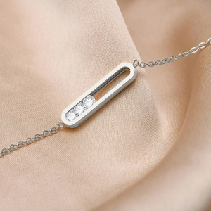 Detailed macro view of silver chain bracelet with sliding gems on beige satin fabric