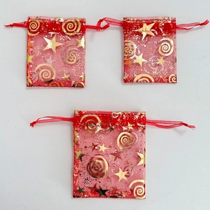 Close-up of red organza gift bags with gold stars and spirals with drawstring detail