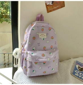 Detail of purple strawberry backpack with heart patterns and white plush pendant