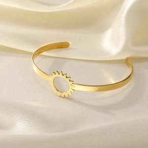 Detailed macro of gold open cuff bracelet featuring a sun-shaped镂空 cutout decoration