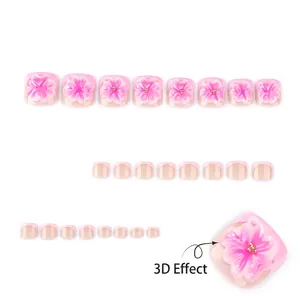 Pink press-on toenails featuring 3D floral designs and gold beads on a white background