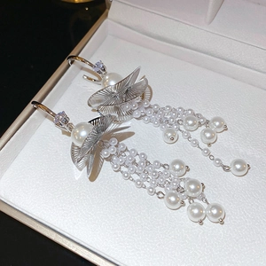 Detailed macro of silver zircon pearl tassel earrings in a cream leather gift jewelry box