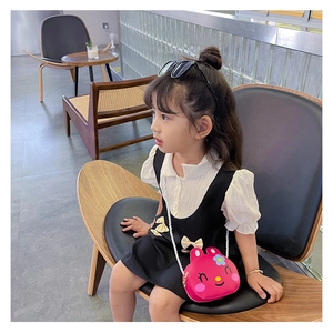 Detail of cute rabbit crossbody bag in rose red worn by a child in a cafe setting