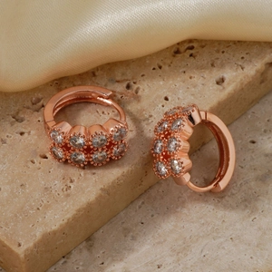 Makroaufnahme von roségoldenen Creolen mit doppelreihigen Zirkonia auf Seidenhintergrund
