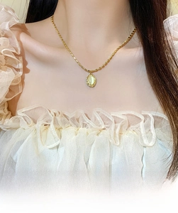 Close-up of a vintage cat-eye stone pendant on a gold bead chain for a retro luxury look