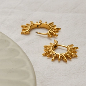 Détails de boucles d'oreilles créoles en acier doré avec bords texturés effet soleil