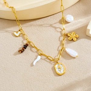 Golden necklace set with floral, heart, pearl and tiger eye stone pendants on beige texture