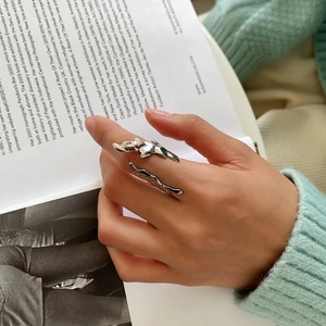 Detail of liquid metal style silver adjustable ring worn on hand with cozy knitwear