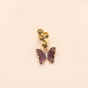 Detailed close-up of golden metal butterfly pendant with purple crystals and small diamonds