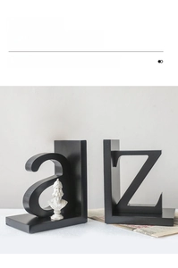Close-up of black 'a' and 'z' alphabet bookends with a white bust statue on a desk