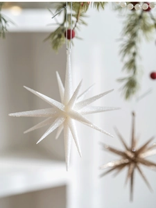 Close-up of white glittery multi-pointed star Christmas tree ornament with pine decor.