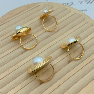 Chic gold-plated flower rings with imitation pearls on a beige striped jewelry tray