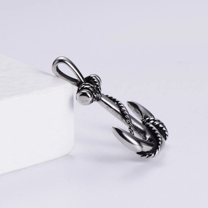 Detail shot of vintage stainless steel anchor pendant with rope texture on white prop