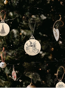 Close-up of wooden Christmas ornaments with engraved patterns hanging on a tree branch