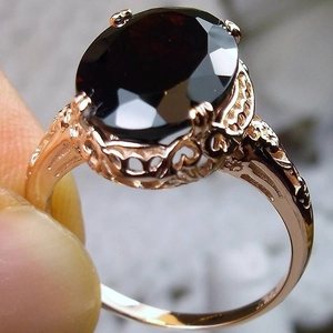 Macro shot of oval-cut red gemstone ring with rose gold hollow-out carving details