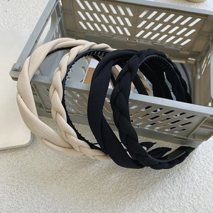 Detail of beige and black braided sponge headbands inside a grey storage basket