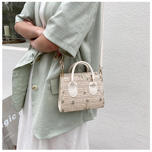 Detail of straw woven bag with green floral embroidery and adjustable PU strap